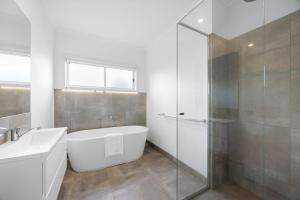 a white bathroom with a tub and a shower at Spacious 4-Bedroom Retreat in Mansfield +17 photos