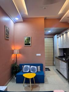 a living room with a blue couch and a yellow table at Good vibes only gaur city center studio apartment in Ghaziabad