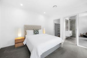 a white bedroom with a large bed and a bathroom at Spacious 4-Bedroom Retreat in Mansfield