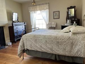 a bedroom with a bed and a dresser and a window at Manoir Hamilton in New Carlisle