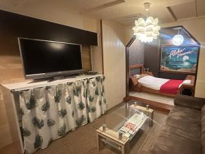 a living room with a flat screen tv and a couch at Hotel Maile in Tokyo
