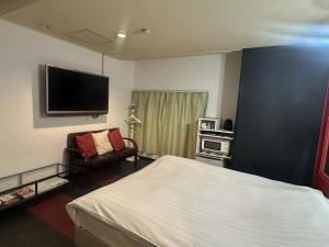 a bedroom with a bed and a flat screen tv at Hotel Maile in Tokyo