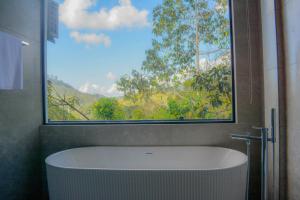 a bath tub in a bathroom with a large window at 3Arch Eco Cottage Ella in Ella +291 photos