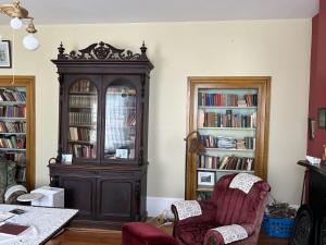 a large wooden cabinet in a living room with two chairs at Manoir Hamilton in New Carlisle