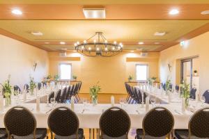 uma sala de conferências com mesas e cadeiras e um lustre em Landhotel Sonnenhof em Ossig