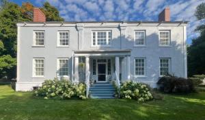 a white house with a front door and stairs at Manoir Hamilton in New Carlisle