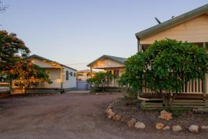 a row of houses with trees in front of a driveway at Longreach Tourist Park in Longreach
