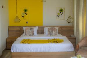 a bedroom with a large bed with a yellow wall at 3Arch Eco Cottage Ella in Ella