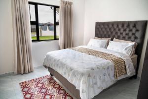a bedroom with a large bed and a window at Little leisures in Matsapha