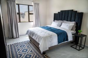 a bedroom with a large bed with a large window at Little leisures in Matsapha