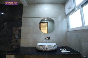 ein Badezimmer mit einem runden Waschbecken und einem Spiegel in der Unterkunft Hotel Arrya Inn in Nāi