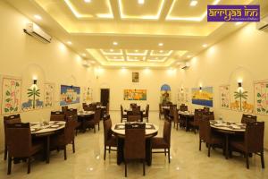 ein Restaurant mit Tischen und Stühlen und Gemälden an den Wänden in der Unterkunft Hotel Arrya Inn in Nāi