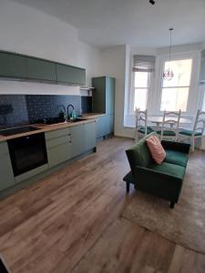 a living room with a green couch and a kitchen at Victoria Guest Apartment in Ramsgate +17 photos