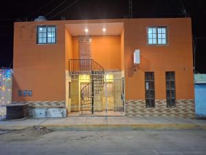 an orange building with a staircase on the side of it at Hospedaje AMAPI - San José in El Carmen
