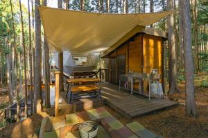 a cabin in the woods with a tent on a deck at エメラルドの森 in Izunokuni