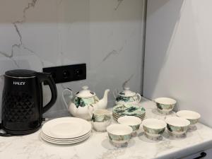 a counter with plates and cups and a tea kettle at Atamura 1 in Karagandy