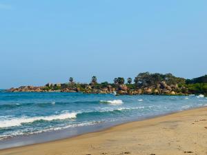 a beach with a group of rocks in the water at Friendly Waves Resort Arugambay in Pottuvil