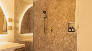 a shower in a bathroom with a stone wall at Sunyata Resort Siargao in Catagnan +33 photos