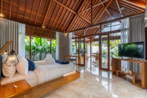 a bedroom with a large bed and a flat screen tv at Villa Al-Mulk in Ubud