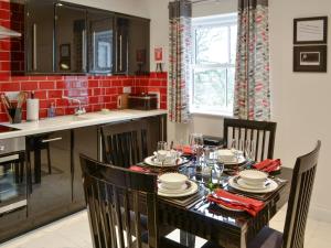 a dining room with a table with chairs and a kitchen at Railway Cuttings in Falstone