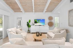 a living room with white furniture and a flat screen tv at Wait N' Sea- Previously Millertime home in Captiva
