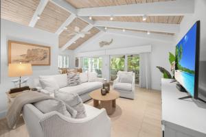 a living room with white furniture and a flat screen tv at Wait N' Sea- Previously Millertime home in Captiva