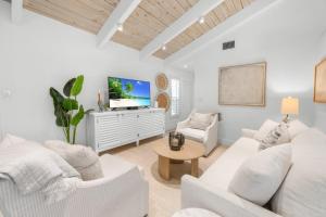 a living room with white furniture and a flat screen tv at Wait N' Sea- Previously Millertime home in Captiva