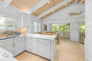 a kitchen with white cabinets and a wooden ceiling at Wait N' Sea- Previously Millertime home in Captiva +31 photos