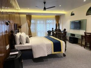 a bedroom with a large bed and a television at Cochrane Place By Teesta Hotels in Kurseong