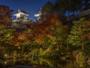 a japanese garden at night with a tower in the background at UAN kanazawa in Kanazawa