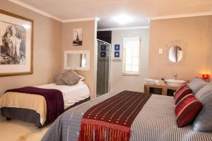 a bedroom with two beds and a bathroom with a sink at Red olive guesthouse in Parys