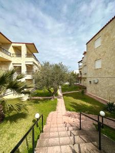a walkway next to a building with trees and grass at Avra Yard Suites in Pefkochori