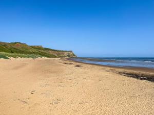 a sandy beach with the ocean in the background at The Badger Sett in Hinderwell