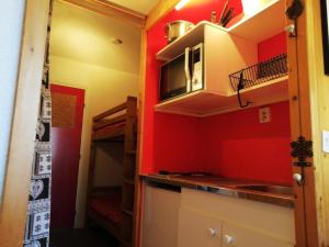 a small kitchen with red walls and a microwave at Résidence Armoise - Studio 3 personnes à Arc 1800 en centre station, proche des pistes et des commerces, dans le village des Villards MAE-1982 in Arc 1800