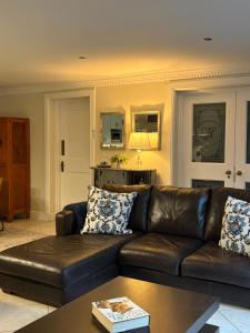 a living room with a brown leather couch and a kitchen at Vitry Country Estate in Gqeberha