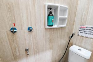a bathroom with a toilet with a bottle on the wall at Queen Residence Ancol RedPartner in Jakarta