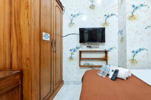 a bedroom with a bed and a tv on a wall at Queen Residence Ancol RedPartner in Jakarta +9 photos