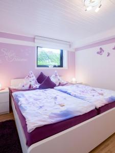 a bedroom with a large white bed with purple pillows at Ferienwohnung Alexandra in Mettlach