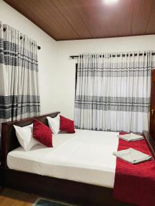 a bedroom with a white bed with red pillows at The Grand Residence in Ella