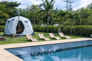 a tent and lounge chairs next to a swimming pool at Ocean Front Villa Ishigakijima Ⅰ in Ishigaki Island