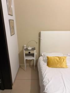 a bed with a yellow pillow next to a side table at La Cosette Janvier in Mios