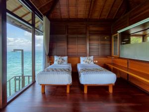 two beds in a room with a view of the ocean at Leebong Island Resort in Leebong