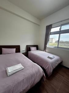 two beds in a room with a window at Kinmen Xinya Homestay in Jinning
