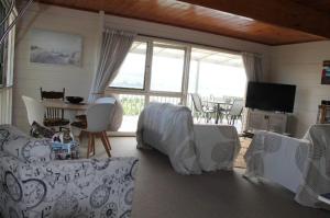 a living room with couches and a table and a television at Bay view breeze in Raglan