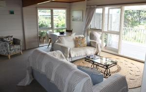 a living room with white furniture and a table at Bay view breeze in Raglan