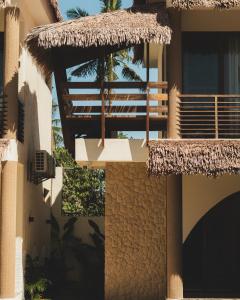 a building with a straw roof and a balcony at Sunyata Resort Siargao in Catagnan