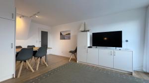 a living room with a table and a flat screen tv at Ferienwohnung Uns Huus in Langeoog