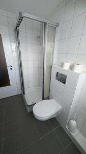a white bathroom with a toilet and a shower at Ferienwohnung Uns Huus in Langeoog +28 photos