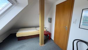 a small attic room with a bed and a wooden door at Ferienwohnung Uns Huus in Langeoog