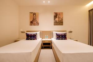 two beds in a hotel room with paintings on the walls at Keys Select By Lemon Tree Hotels, Vadodara in Vadodara +32 photos